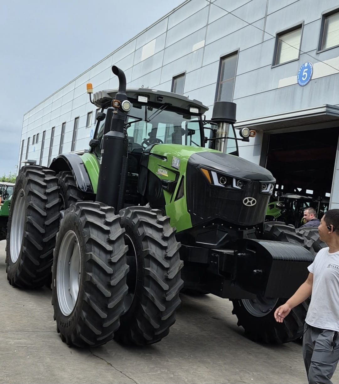 Large green tractor outside a Chinese agricultural machinery factory during a supplier visit